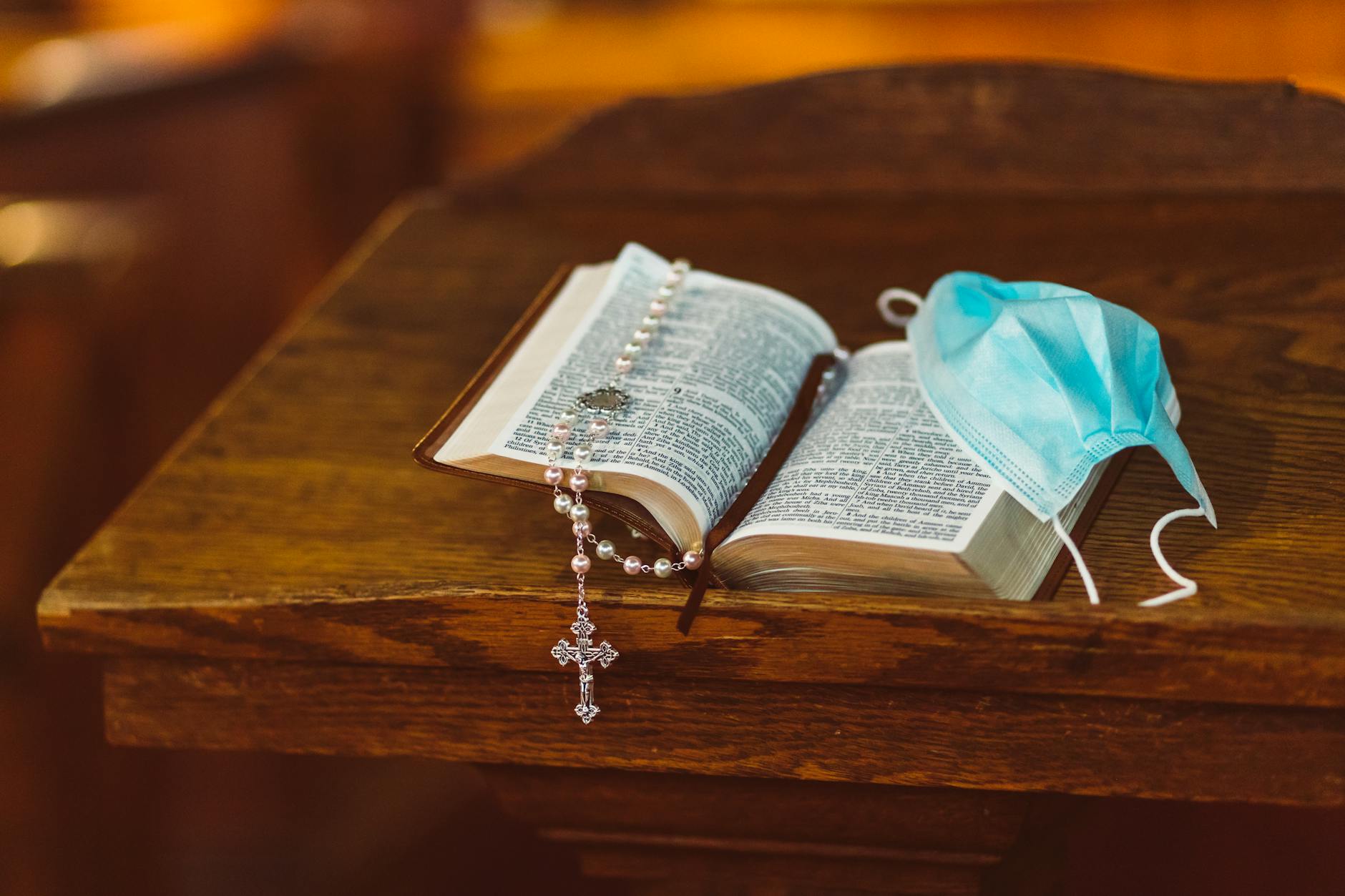 rosary and face mask on top of a bible